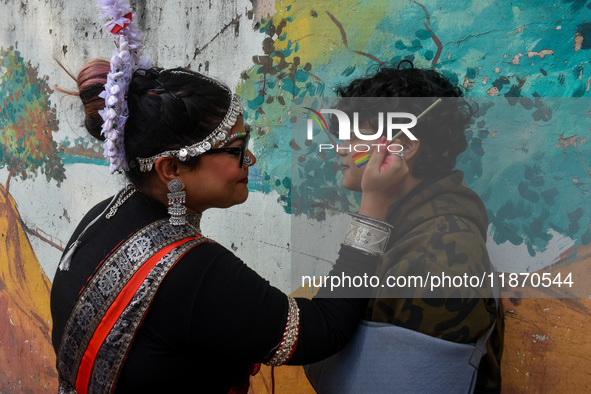 A participant paints pride flags on the cheeks of others during the annual pride walk in Kolkata, India, on December 15, 2024. 