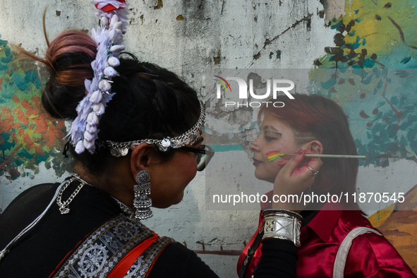 A participant paints pride flags on the cheeks of others during the annual pride walk in Kolkata, India, on December 15, 2024. 