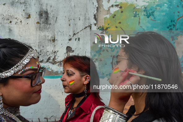 A participant paints pride flags on the cheeks of others during the annual pride walk in Kolkata, India, on December 15, 2024. 