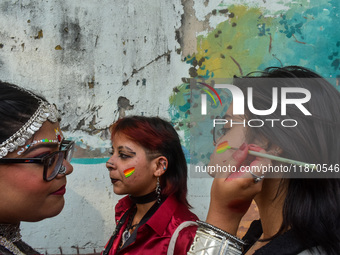 A participant paints pride flags on the cheeks of others during the annual pride walk in Kolkata, India, on December 15, 2024. (