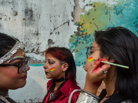 A participant paints pride flags on the cheeks of others during the annual pride walk in Kolkata, India, on December 15, 2024. (