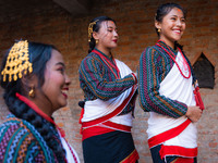 A girl in traditional Newari attire ties her friend's hair. (