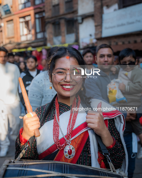 A girl poses for a camera while playing the 'Dhime' Newari musical instrument in Bhaktapur, Nepal. 