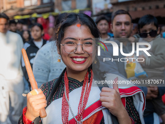 A girl poses for a camera while playing the 'Dhime' Newari musical instrument in Bhaktapur, Nepal. (