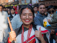 A girl poses for a camera while playing the 'Dhime' Newari musical instrument in Bhaktapur, Nepal. (