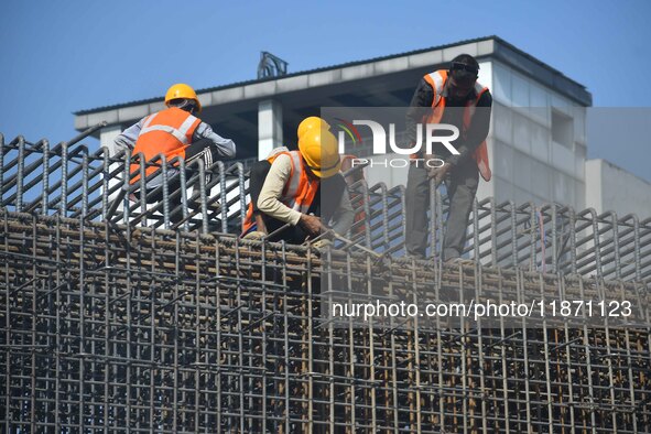 Workers work on the construction of a bridge in Guwahati, India, on December 15, 2024. 