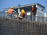 Workers work on the construction of a bridge in Guwahati, India, on December 15, 2024. (