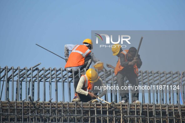 Workers work on the construction of a bridge in Guwahati, India, on December 15, 2024. 