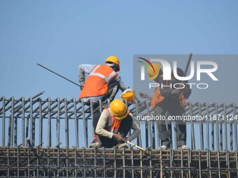 Workers work on the construction of a bridge in Guwahati, India, on December 15, 2024. (