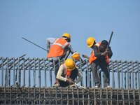 Workers work on the construction of a bridge in Guwahati, India, on December 15, 2024. (