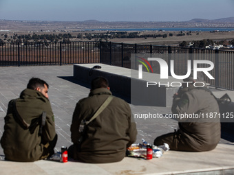 Israeli soldiers and Israeli civilians visit a lookout point next to the boundary fence delineating the UN-patrolled buffer zone between Isr...