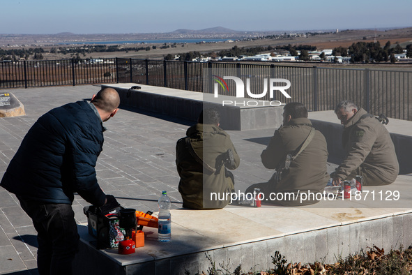 Israeli soldiers and civilians visit a lookout point next to the boundary fence delineating the UN-patrolled buffer zone between Israel and...