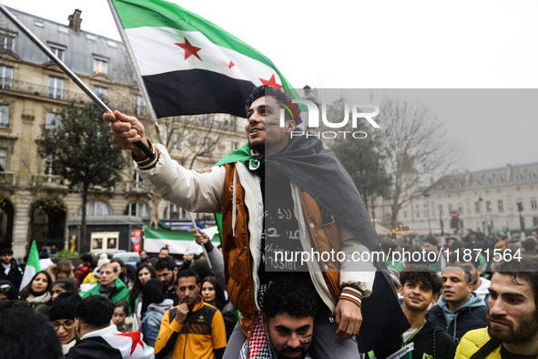 A demonstrator holds flags and banners during a demonstration in support of the Syrian people and to celebrate the fall of Syrian President...