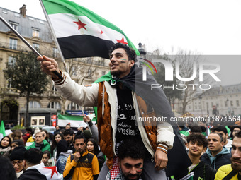 A demonstrator holds flags and banners during a demonstration in support of the Syrian people and to celebrate the fall of Syrian President...