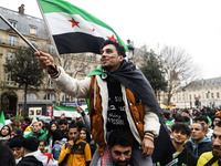 A demonstrator holds flags and banners during a demonstration in support of the Syrian people and to celebrate the fall of Syrian President...