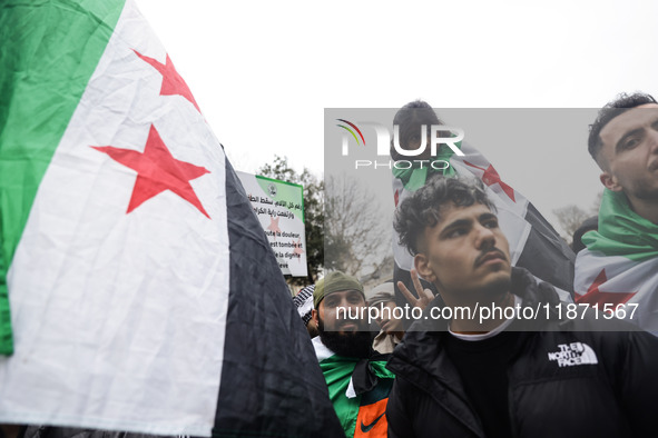 A demonstrator holds flags and banners during a demonstration in support of the Syrian people and to celebrate the fall of Syrian President...