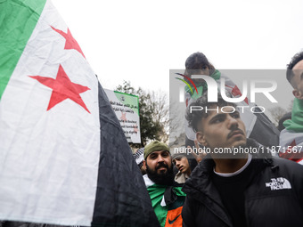 A demonstrator holds flags and banners during a demonstration in support of the Syrian people and to celebrate the fall of Syrian President...