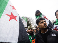 A demonstrator holds flags and banners during a demonstration in support of the Syrian people and to celebrate the fall of Syrian President...