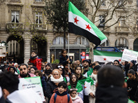 A demonstrator holds flags and banners during a demonstration in support of the Syrian people and to celebrate the fall of Syrian President...