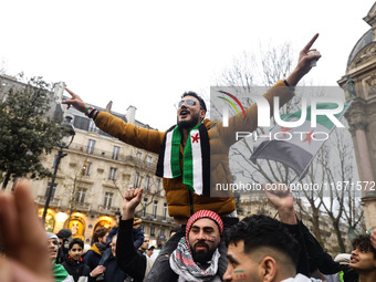 A demonstrator holds flags and banners during a demonstration in support of the Syrian people and to celebrate the fall of Syrian President...