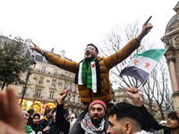 A demonstrator holds flags and banners during a demonstration in support of the Syrian people and to celebrate the fall of Syrian President...