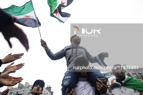 A demonstrator holds flags and banners during a demonstration in support of the Syrian people and to celebrate the fall of Syrian President...