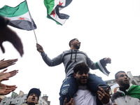 A demonstrator holds flags and banners during a demonstration in support of the Syrian people and to celebrate the fall of Syrian President...