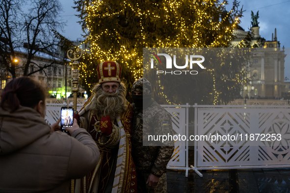 A Ukrainian soldier takes a photo with a man dressed as St. Nicholas near the Main Christmas tree in Lviv, Ukraine, on December 15, 2024. 