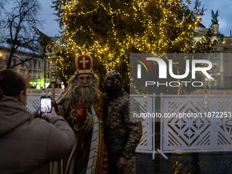 A Ukrainian soldier takes a photo with a man dressed as St. Nicholas near the Main Christmas tree in Lviv, Ukraine, on December 15, 2024. (