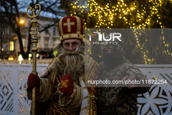 A Ukrainian soldier takes a photo with a man dressed as St. Nicholas near the Main Christmas tree in Lviv, Ukraine, on December 15, 2024. 