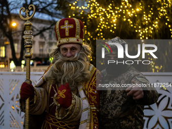 A Ukrainian soldier takes a photo with a man dressed as St. Nicholas near the Main Christmas tree in Lviv, Ukraine, on December 15, 2024. (