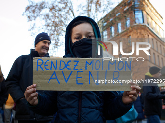 A child holds a placard reading 'Give me back my future'. Between 100 and 1500 people gather in Toulouse, France, on December 15, 2024, to p...