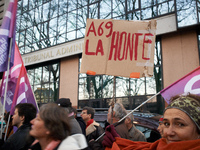 A woman holds a cardboard sign reading 'Shame on the A69' in front of the Administrative Court of Toulouse. Between 1,000 and 1,500 people g...