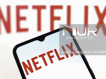 The Netflix logo appears on the screen of a smartphone and in the background on the computer screen in Reno, United States, on December 15,...