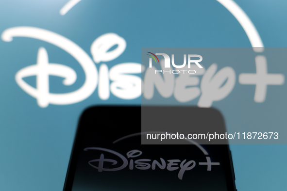 The Disney Plus logo appears on the screen of a smartphone and in the background on the computer screen in Reno, United States, on December...