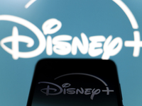 The Disney Plus logo appears on the screen of a smartphone and in the background on the computer screen in Reno, United States, on December...