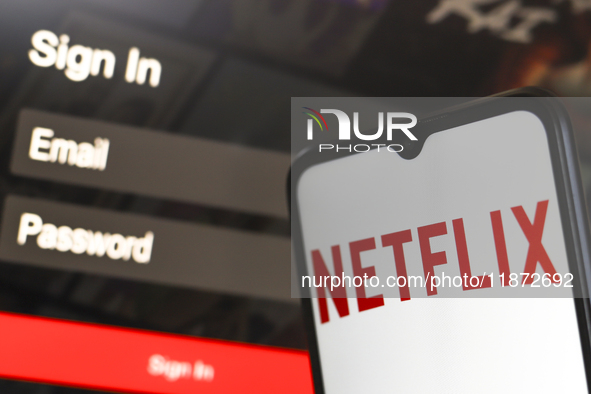 The Netflix logo appears on a smartphone screen next to a login screen with email and password in Reno, United States, on December 15, 2024....