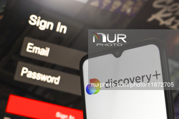 The Discovery Plus logo appears on a smartphone screen next to a login screen with email and password in Reno, United States, on December 15...