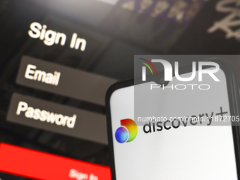 The Discovery Plus logo appears on a smartphone screen next to a login screen with email and password in Reno, United States, on December 15...