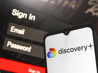 The Discovery Plus logo appears on a smartphone screen next to a login screen with email and password in Reno, United States, on December 15...