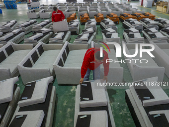 A worker produces sofas for sale to Europe and the United States in a furniture workshop in Suqian, Jiangsu province, China, on December 15,...