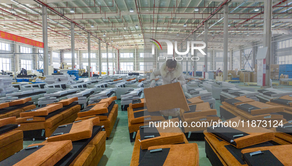 A worker produces sofas for sale to Europe and the United States in a furniture workshop in Suqian, Jiangsu province, China, on December 15,...