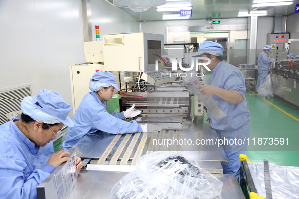 Workers work on the production line of a pharmaceutical packaging workshop in Lianyungang, Jiangsu province, China, on December 16, 2024. 