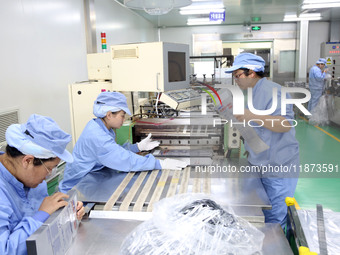 Workers work on the production line of a pharmaceutical packaging workshop in Lianyungang, Jiangsu province, China, on December 16, 2024. (