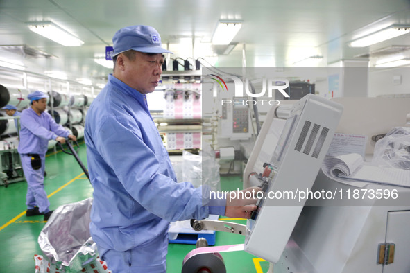 A worker works on the production line of a pharmaceutical packaging workshop in Lianyungang, China, on December 16, 2024. 