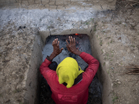 A worker warms himself as others prepare date jaggery after collecting juice from date palm trees in Magura, Bangladesh, on January 16, 2024...