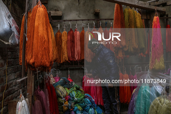 Maqsood Ahmad adjusts threads inside a dyeing center in Srinagar, Jammu and Kashmir, on December 16, 2024. Kashmiris dye fabric and threads...