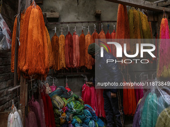 Maqsood Ahmad adjusts threads inside a dyeing center in Srinagar, Jammu and Kashmir, on December 16, 2024. Kashmiris dye fabric and threads...