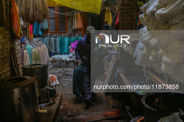 Maqsood Ahmad carries threads inside a dyeing center in Srinagar, Jammu and Kashmir, on December 16, 2024. Kashmiris dye fabric and threads...