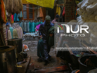 Maqsood Ahmad carries threads inside a dyeing center in Srinagar, Jammu and Kashmir, on December 16, 2024. Kashmiris dye fabric and threads...